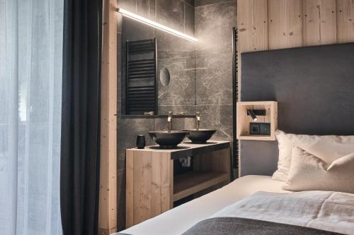 a bedroom with a bed and a bathroom with two sinks at Tenne Chalets in Racines