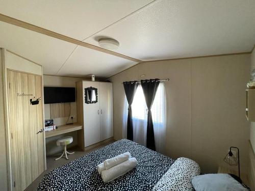 a bedroom with a bed and a window at Holiday Park Caravan Fluffy in Harts Holiday Park in Leysdown-on-Sea
