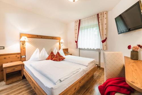 セルヴァ・ディ・ヴァル・ガルデーナにあるAmonit - Your Dolomites Homeのベッドとテレビが備わるホテルルームです。