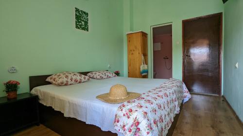 a bedroom with a bed with a straw hat on it at Stoyanovi Guest House in Chernomorets