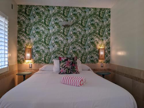 een slaapkamer met een groot wit bed en een groene muur bij El Rancho Motel in San Diego