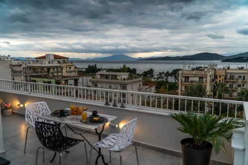 een balkon met een tafel en stoelen en uitzicht op het water bij Sea View luxury apartment in Volos