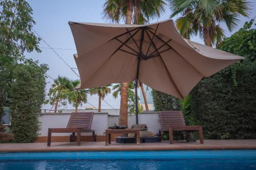 利雅德的住宿－شاليه خاص，游泳池畔的一把遮阳伞和两把椅子