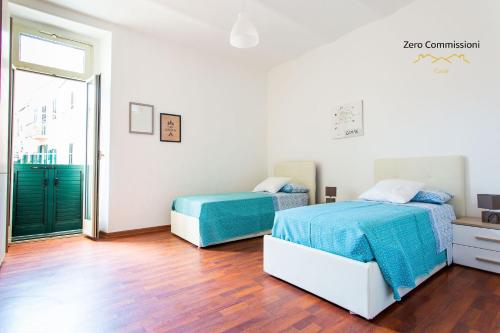 two beds in a white room with wooden floors at Casa Vacanze Licinia - Appartamento centro storico in Citta' Sant'Angelo