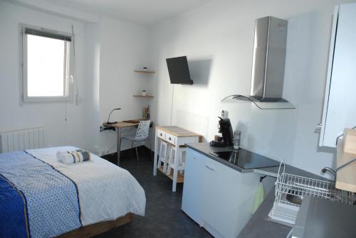 Cette chambre blanche comprend un lit, un bureau et une table. dans l'établissement Studio Nancy quartier Thermal - Parc Sainte-Marie, à Nancy