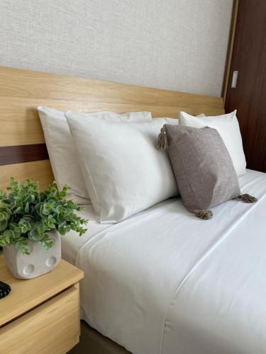 uma cama com almofadas brancas e uma planta sobre uma mesa em Flat PRAIA de Camburi em Vitória