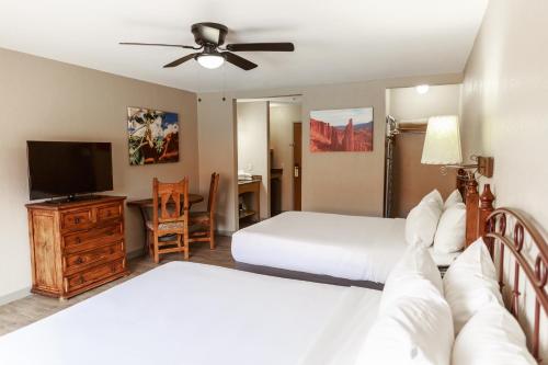 a bedroom with two beds and a flat screen tv at Aarchway Inn in Moab