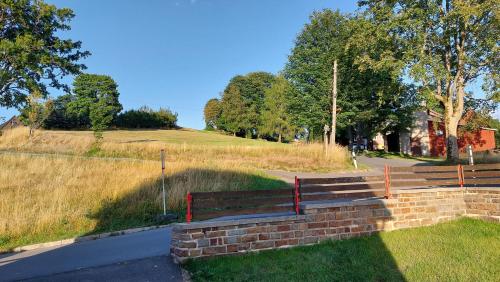 a park bench on a brick wall next to a field at Ferienhäuser Seiffen in Seiffen