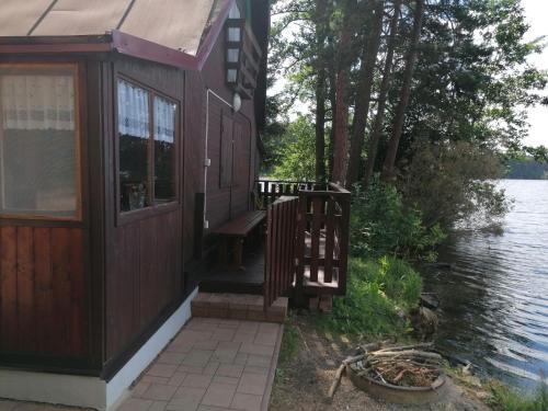 a cabin with a bench on the side of a lake at Chata Florián in Stráž