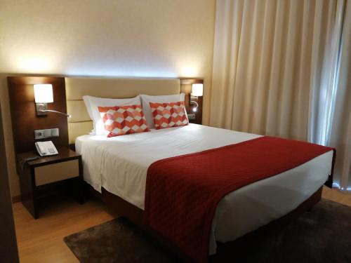 a bedroom with a large bed with a red blanket at Hotel Monaco in Faro