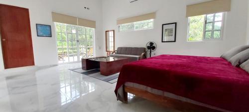 a bedroom with a red bed and a couch at NEW! CASA XOLA Cenote and Fauna Loft in Cozumel