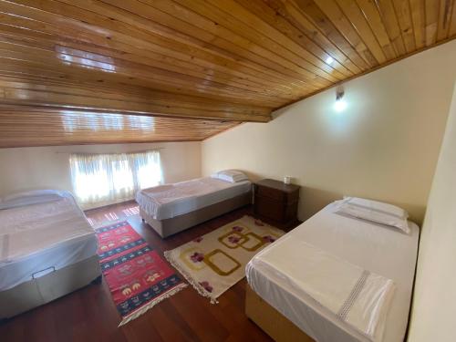 a small room with two beds and a wooden ceiling at Balcı Apart in Çanakkale