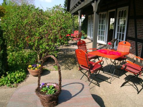 a patio with red chairs and a table with flowers at Landhaus Zum Heidewanderer mit THERMEplus in Bad Bevensen