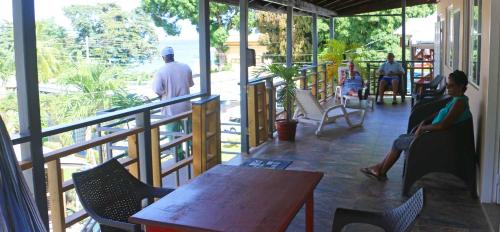 a room with people sitting on chairs and a table at La Casa de Castara in Castara