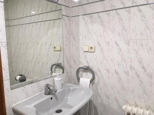 La salle de bains blanche est pourvue d'un lavabo et d'un miroir. dans l'établissement Hostal Rural Oricáin, à Oricáin