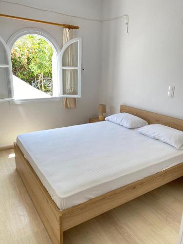a bedroom with a large white bed with two windows at Beautiful House in Front of the Sea in Gázion