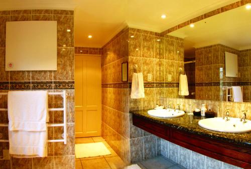 a bathroom with two sinks and a large mirror at Altes Landhaus Country Lodge in Oudtshoorn