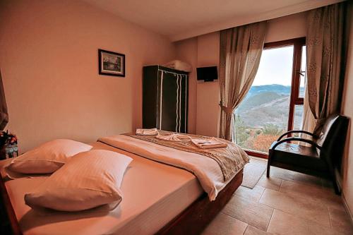 a bedroom with a bed and a large window at Gödence Hotel Restoran Bungalow in Gödence