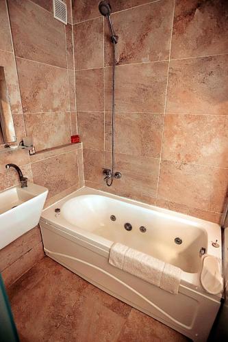 a bathroom with a white tub and a sink at Gödence Hotel Restoran Bungalow in Gödence