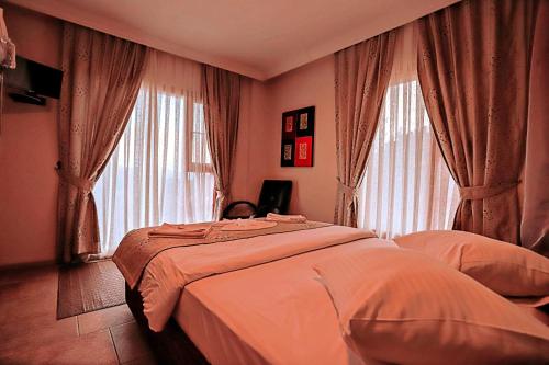 a bedroom with a bed and two large windows at Gödence Hotel Restoran Bungalow in Gödence