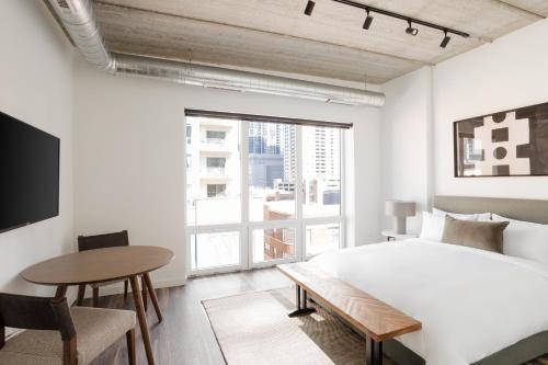 1 dormitorio con cama, mesa y ventana en Sonder The Opal, en Chicago