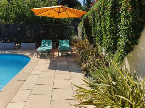 un patio avec deux chaises et un parasol à côté d'une piscine dans l'établissement Gîte 