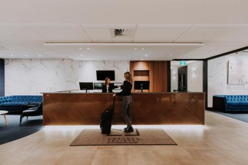 a person with a suitcase standing at a hotel lobby at Hôtel Château Joliette in Joliette