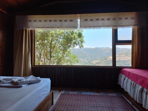 a bedroom with a large window with a view at Gödence Hotel Restoran Bungalow in Gödence