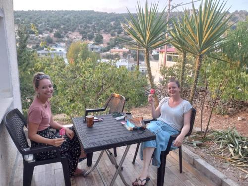 two women sitting at a table on a patio at Mhna guest house in Ajloun
