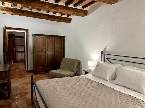 a bedroom with a bed and a chair and a table at Agriturismo Le Querciole in Val d'Orcia in Bagno Vignoni