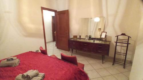 1 dormitorio con cama roja, tocador y espejo en Appartamento Kiwy, en Arsago Seprio