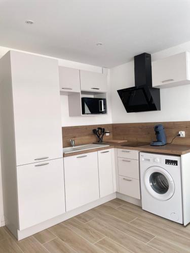 a kitchen with white cabinets and a washing machine at Idéalement situé, vue mer & Parking privée gratuit in Canet-en-Roussillon