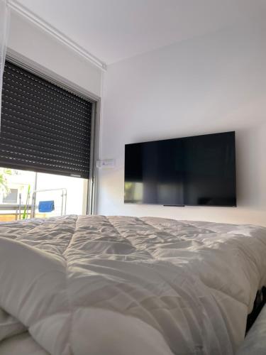 une chambre avec un grand lit et une télévision à écran plat dans l'établissement Idéalement situé, vue mer & Parking privée gratuit, à Canet