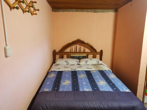 a bedroom with a bed with a wooden headboard at LA TRANQUILIDAD in Mindo