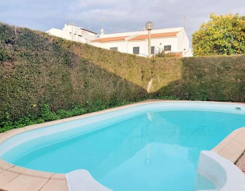 a large blue swimming pool in front of a hedge at LOVELY BEACH HOUSE moradia V4 com piscina in Altura