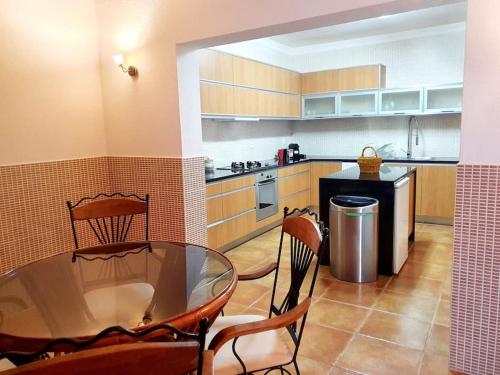a kitchen with a glass table and chairs in it at LOVELY BEACH HOUSE moradia V4 com piscina in Altura