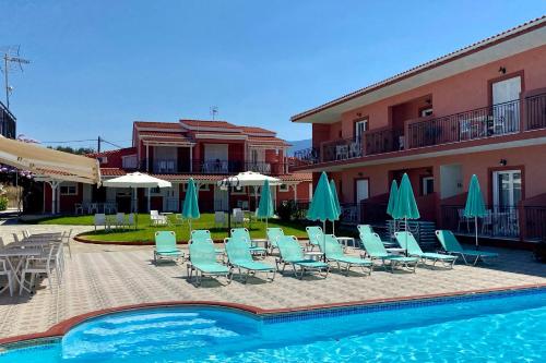 a pool with chairs and umbrellas next to a building at Paradise Studios in Svoronata