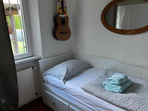 CASA STEFANIA con giardino a LUGANO في Grancia: سرير صغير مع مرآة والغيتار على الحائط