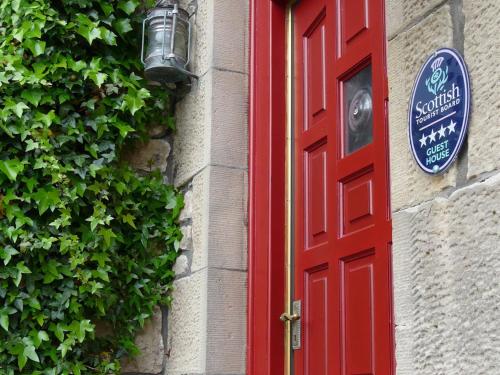 a red door with a sign on the side of a building at Norland B & B in Lossiemouth