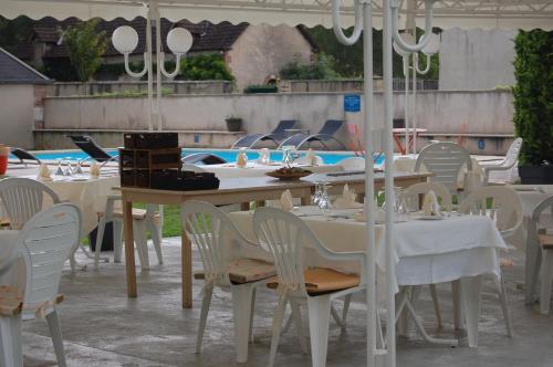 grupa stołów z białymi krzesłami i basenem w obiekcie "Maison D'hôtes du Prieuré" w mieście Vignoux-sur-Barangeon