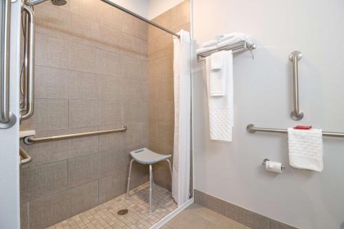 a shower stall with a chair in a bathroom at SureStay Hotel by Best Western Shallotte in Shallotte