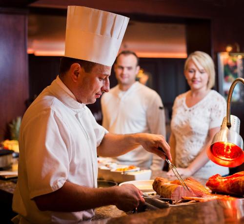 a man in a chef hat preparing meat in a kitchen at Harvey's Point in Donegal