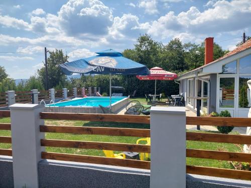 a fence with an umbrella and a swimming pool at Vila Boba Bor in Zlot