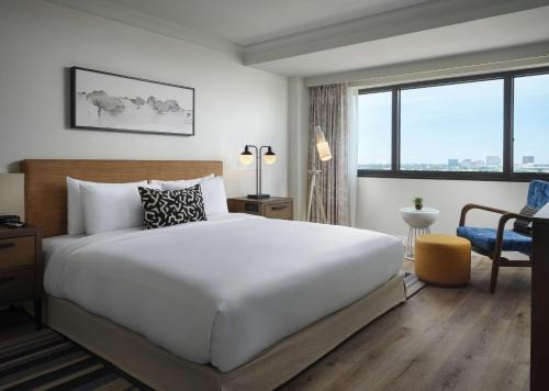 a bedroom with a large white bed and a desk at Sonesta Irvine John Wayne Airport in Irvine