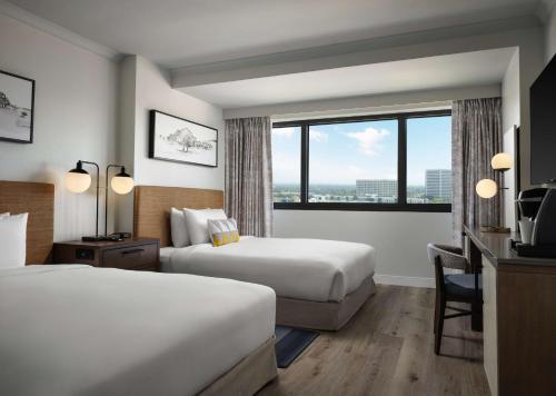 a hotel room with two beds and a window at Sonesta Irvine John Wayne Airport in Irvine