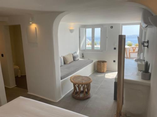 a white room with a bed and a table and a window at Nomikos Villas in Fira