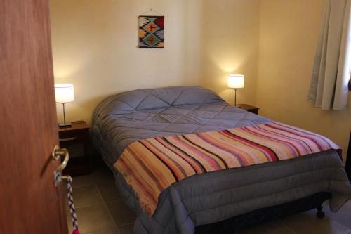 a small bed in a room with two lamps at El Caucillar in Iruya