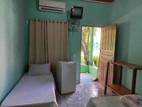 a small room with two beds and a refrigerator at Pousada Cajueiro in Itaúnas