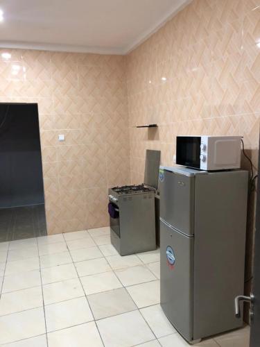 a kitchen with a microwave on top of a refrigerator at Well furnished and very spacious apartment in Wuye in Abuja