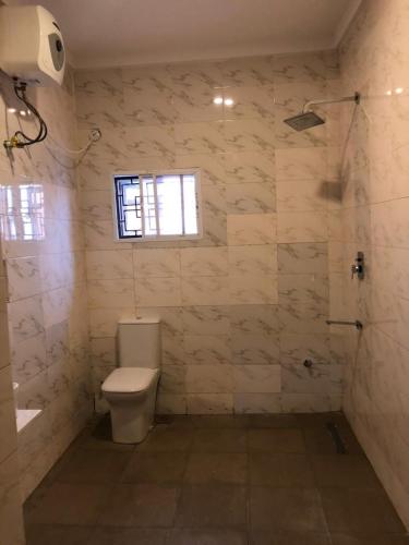 a bathroom with a toilet and a window at Well furnished and very spacious apartment in Wuye in Abuja